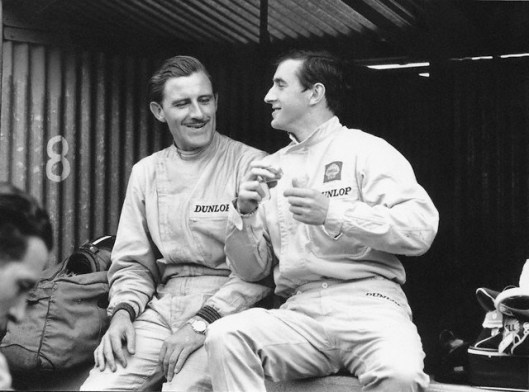27 Jun 1965, Clermont-Ferrand, France --- Graham Hill (left) and Jackie Stewart, both drivers for BRM, sit and talk in the pit stop at the French Grand Prix in Clermont-Ferrand. --- Image by © Schlegelmilch/Corbis